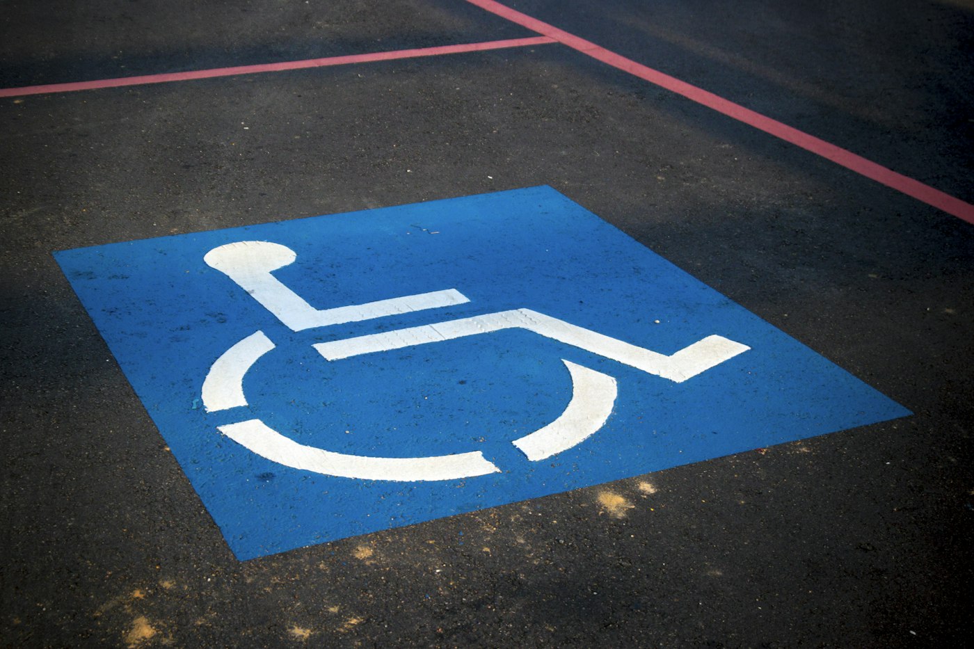Weißes Rollstuhl-Symbol auf blauem Parkplatzboden