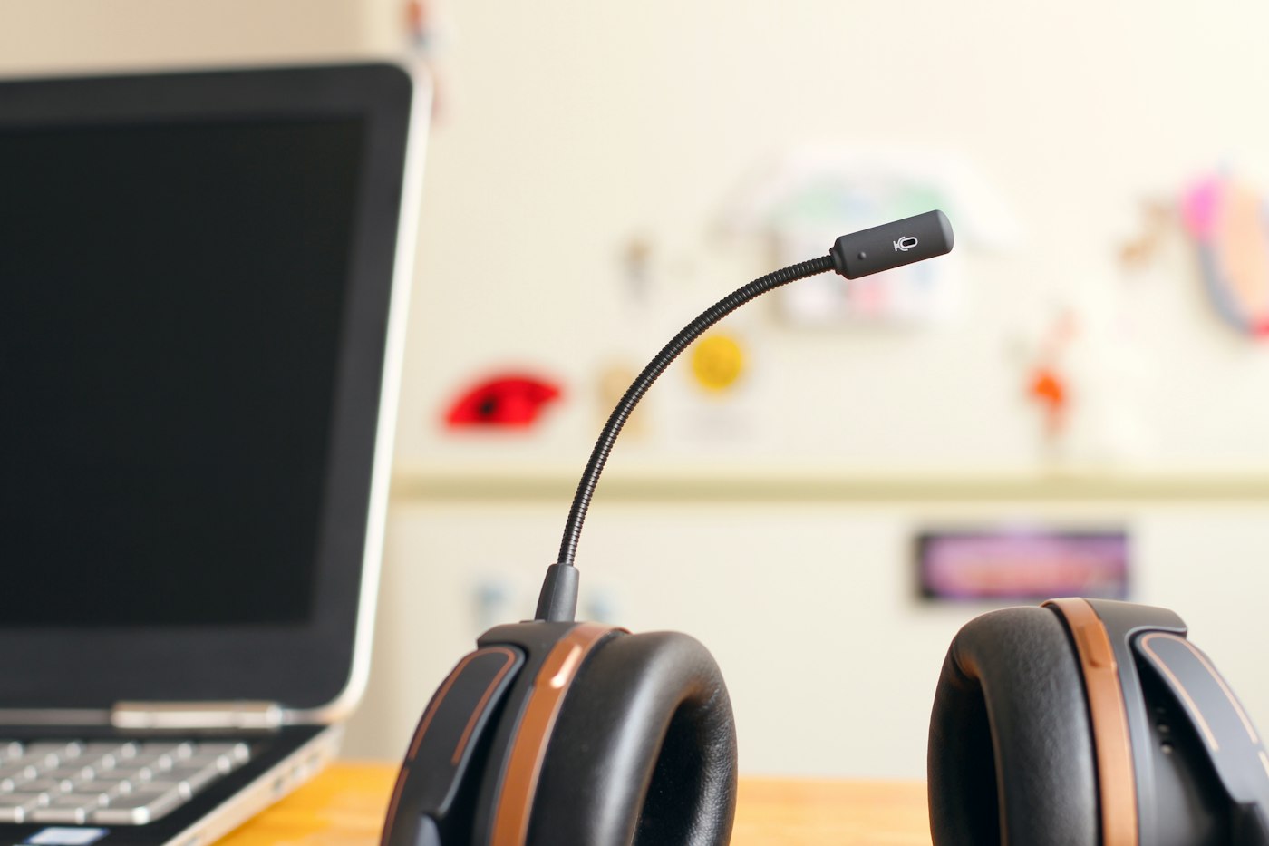 Headset mit Mikrofon vor einem Laptop auf einem Holztisch